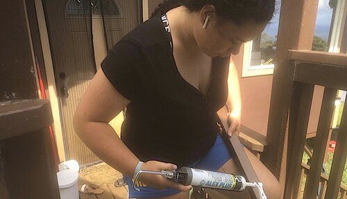 Teenager applying glue to wood as part of a construction project